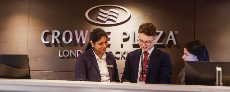 Two Crowne Plaza London hotel employees collaborating at the front desk