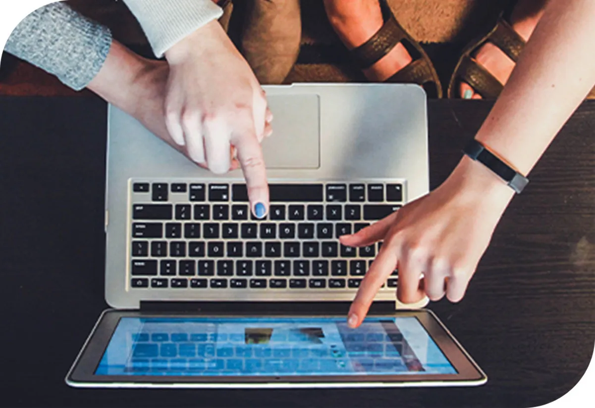 Top down view of people pointing at a laptop screen