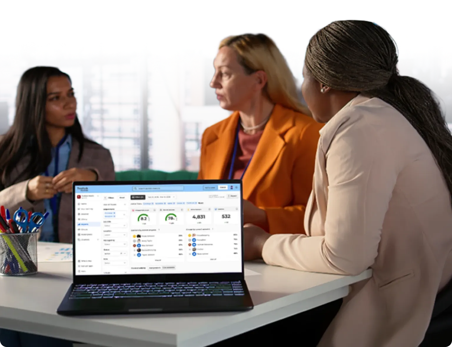 Three colleagues in discussion with a Kahoot 360 admin reporting dashboard open on a laptop
