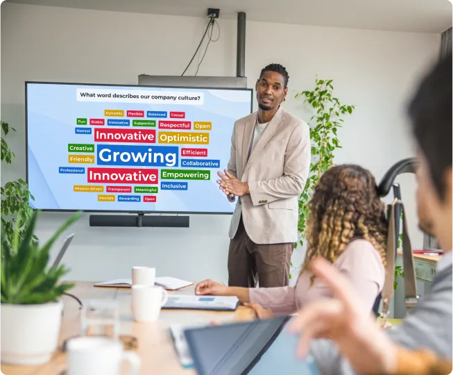 Presenter standing beside a Kahoot word cloud showing company culture responses including Innovative and Growing