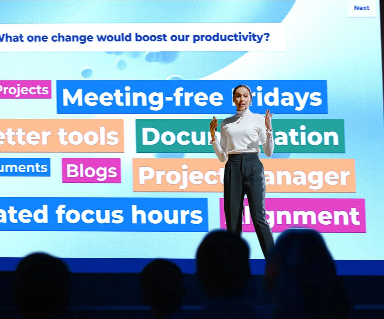 Female presenter presenting on stage in front of audience