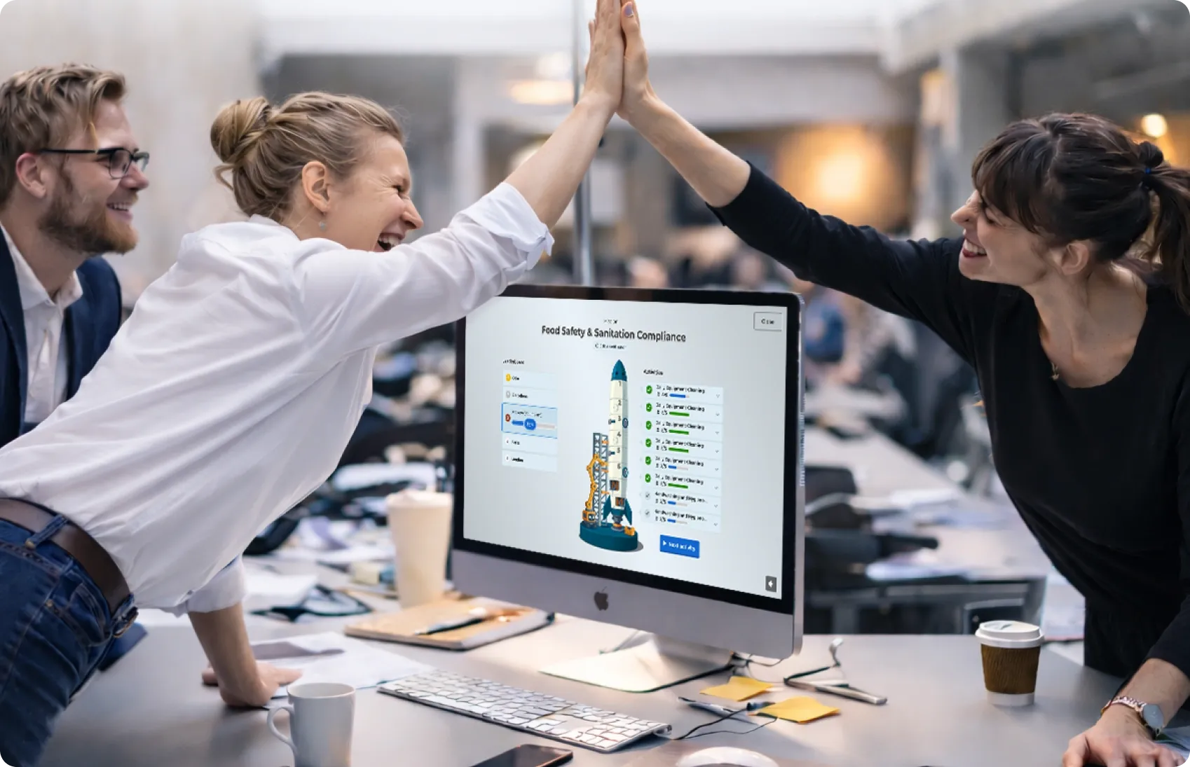 Two colleagues high-fiving across a desk with a Kahoot Food Safety and Sanitation Compliance course on screen
