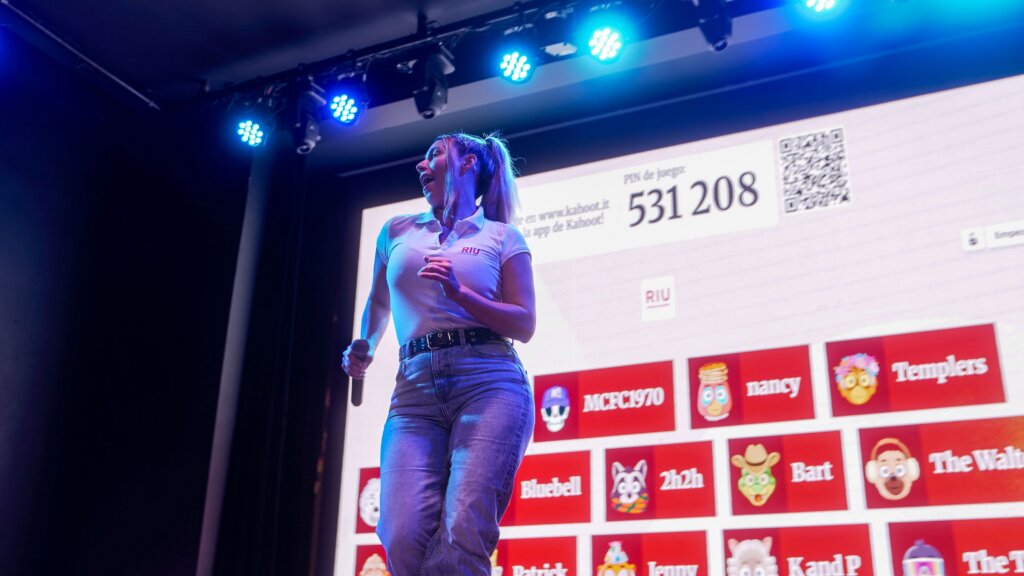 A female RIU entertainer is on stage engaging an audience using Kahoot!