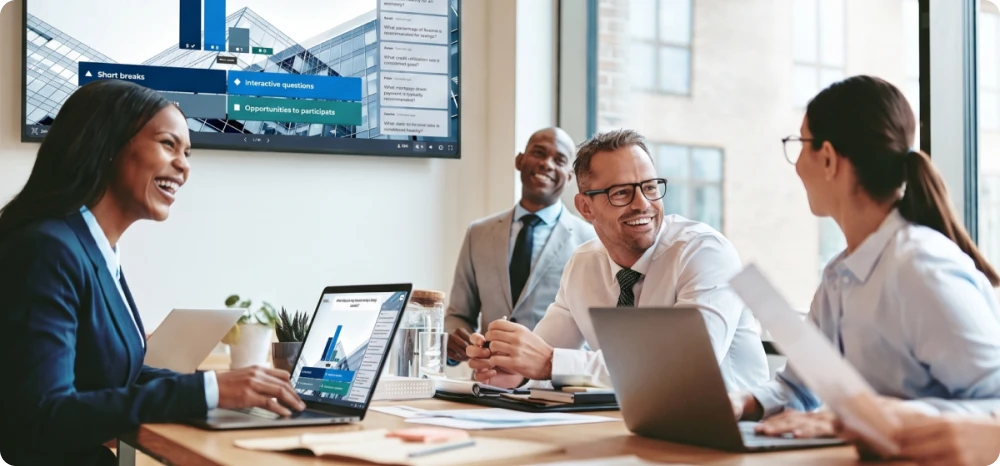 Colleagues in a corporate meeting laugh together with laptops open while a screen behind them displays an interactive Kahoot presentation with questions and results.