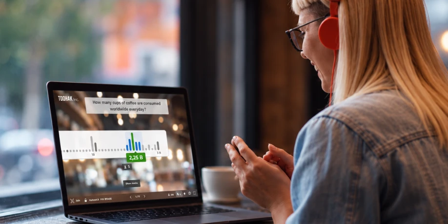 A woman wearing headphones looks at her laptop, which displays a Kahoot poll asking participants to estimate global coffee consumption.